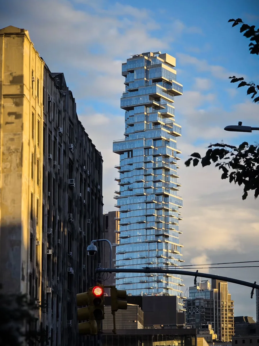 Manhattan’da konsol katlarıyla yükselen cam gökdelen ve sokak manzarası.